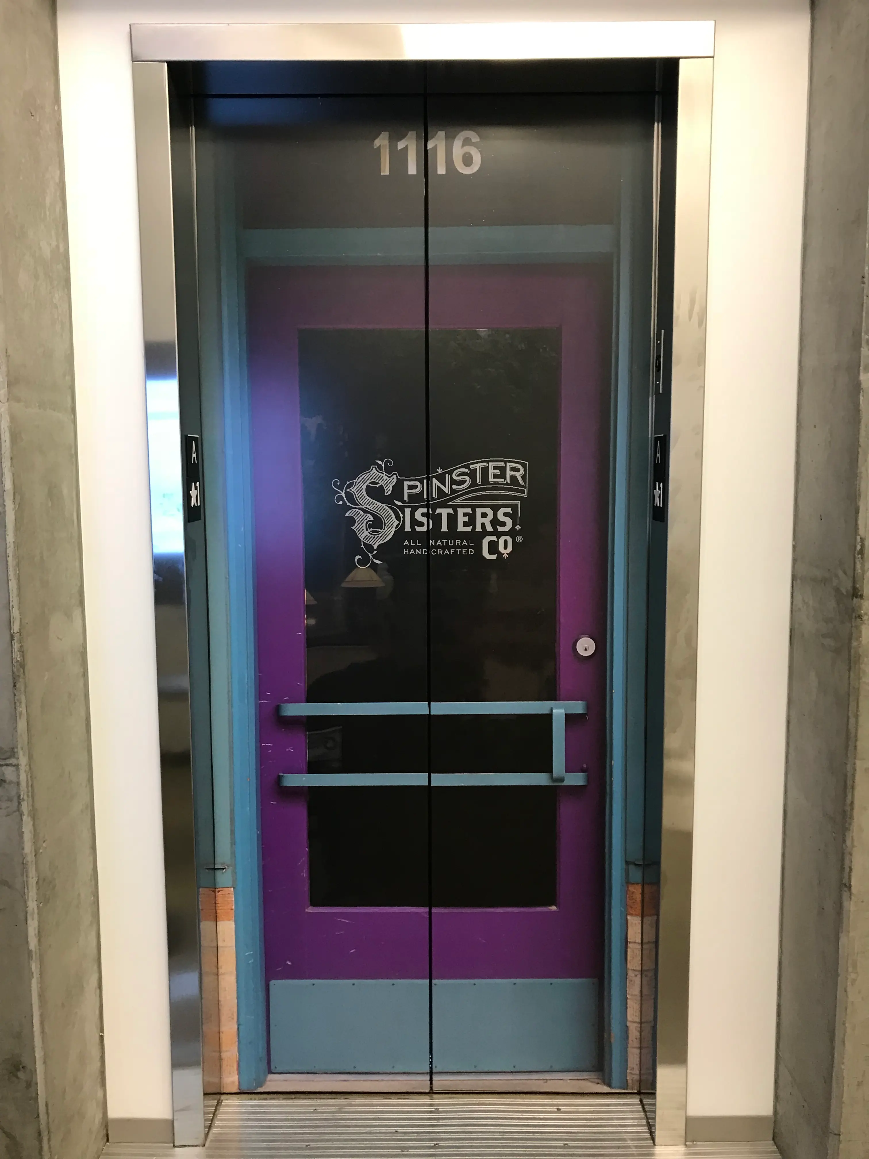 Full-color vinyl elevator door wrap featuring Spinster Sisters Co branding at Intuit campus