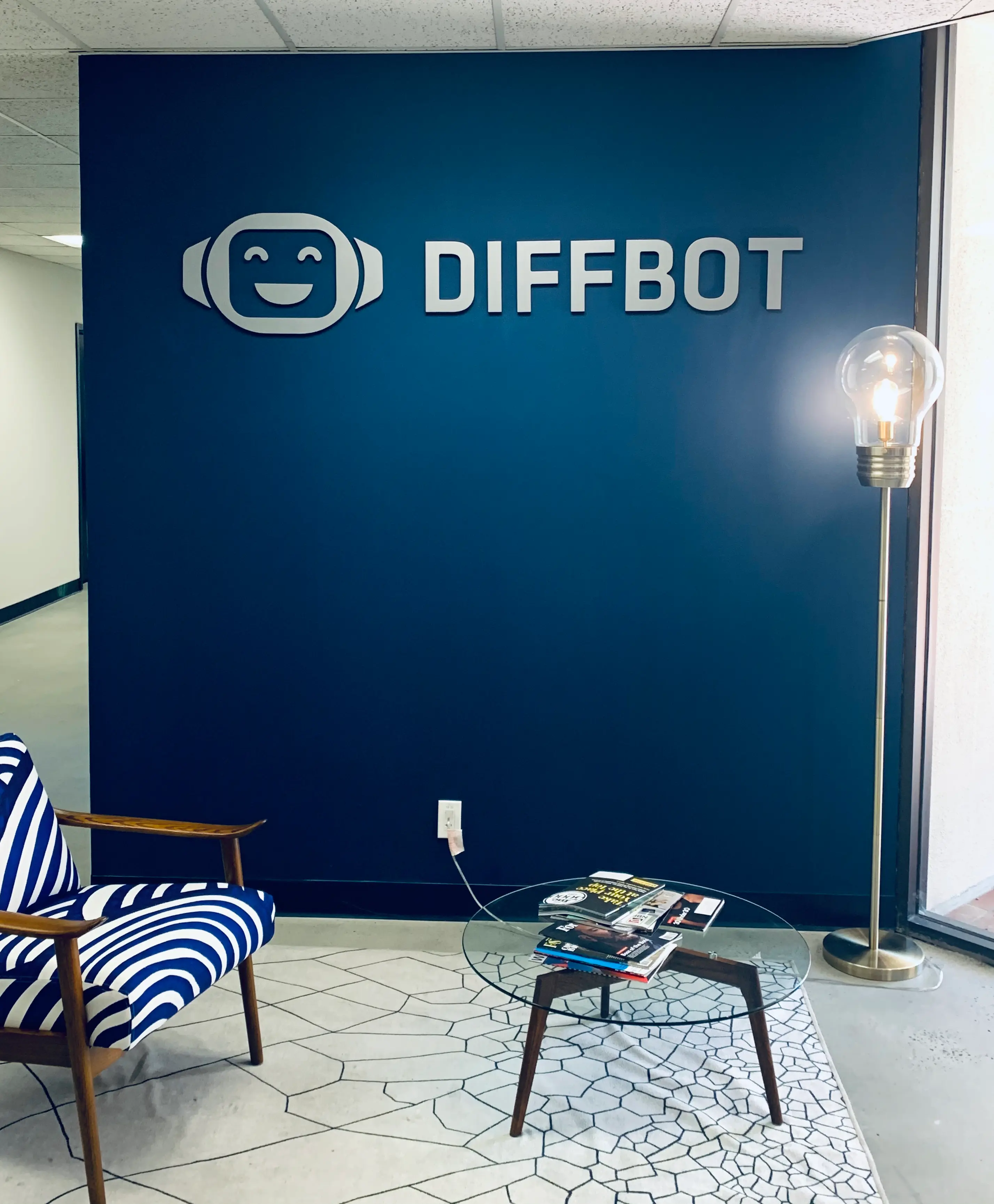Silver dimensional acrylic letters Diffbot lobby sign on navy blue wall